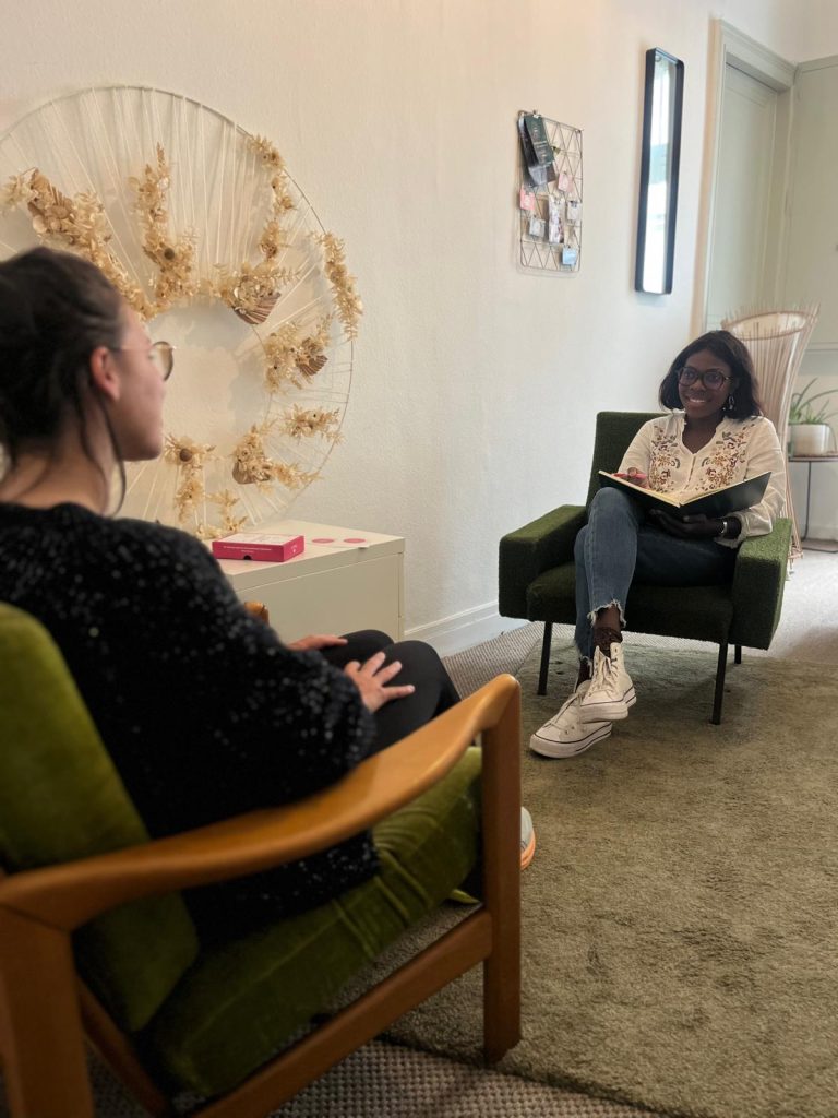 Coach professionnelle assise dans un fauteuil, écoutant une cliente lors d’une séance de coaching